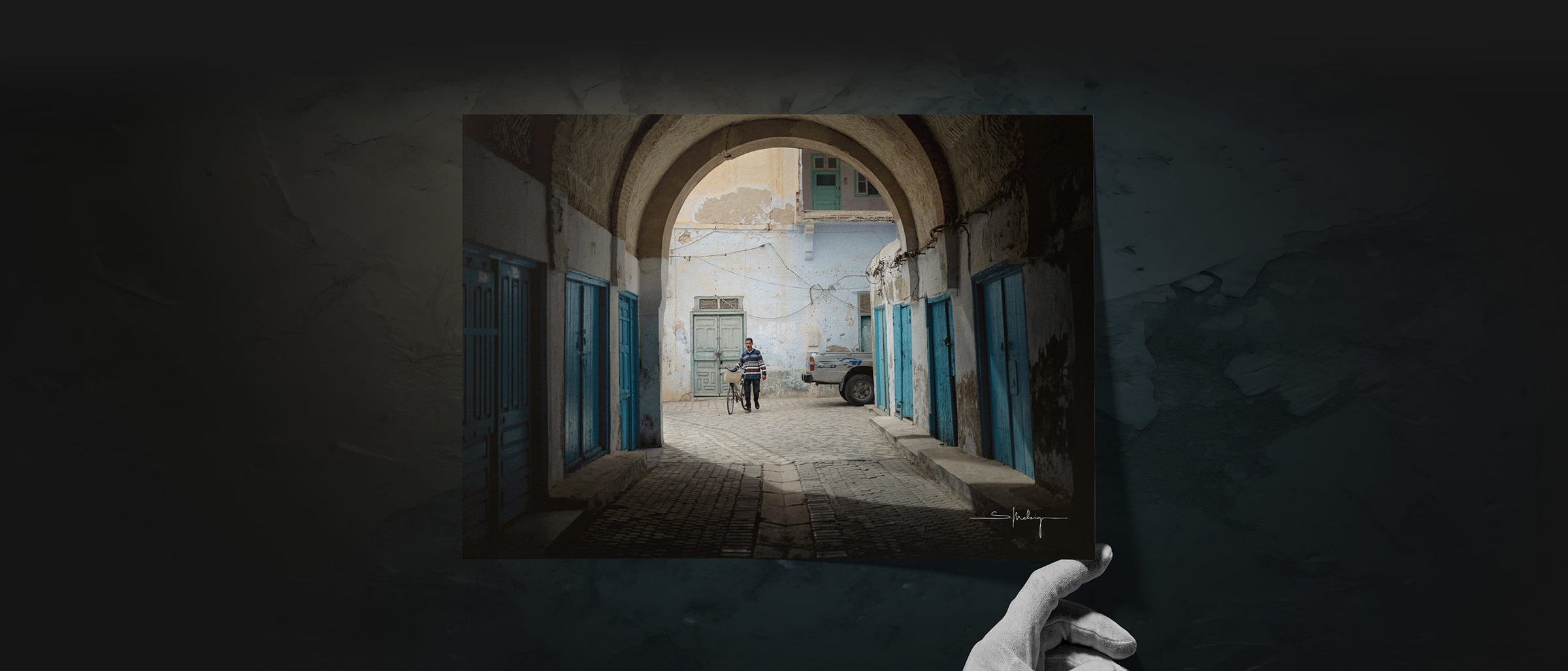 Fine art print of a man with a bicycle in a sunlit Tunisian alley – from the Dustlight Archive collection