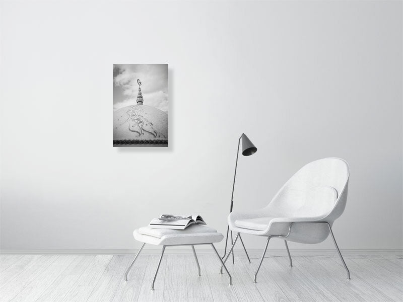 Black and white photograph of a domed rooftop adorned with Arabic calligraphy and topped by a crescent and star finial. The textured surface and cloudy sky create a calm, spiritual atmosphere emphasizing form and symbolism.