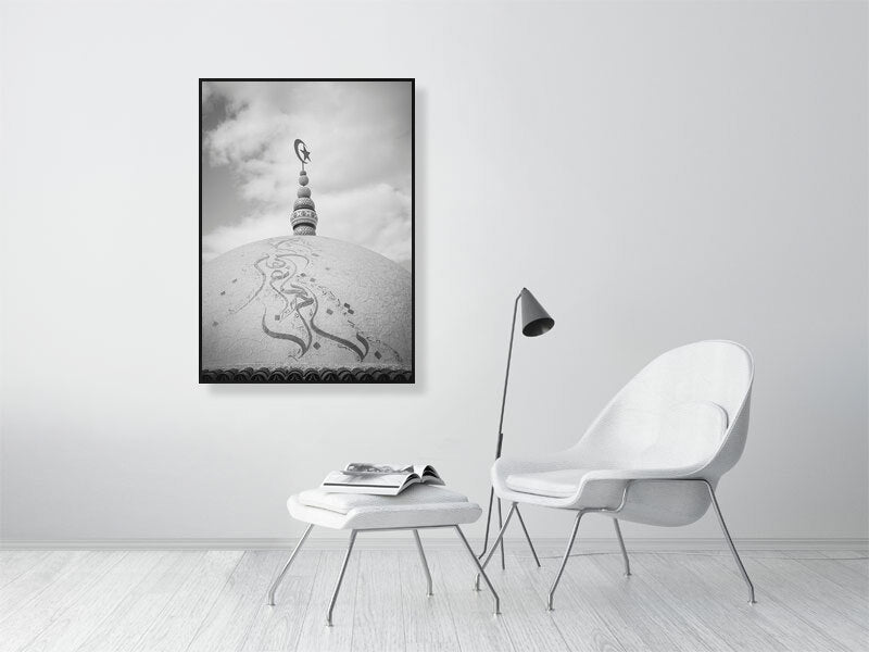 Black and white photograph of a domed rooftop adorned with Arabic calligraphy and topped by a crescent and star finial. The textured surface and cloudy sky create a calm, spiritual atmosphere emphasizing form and symbolism.