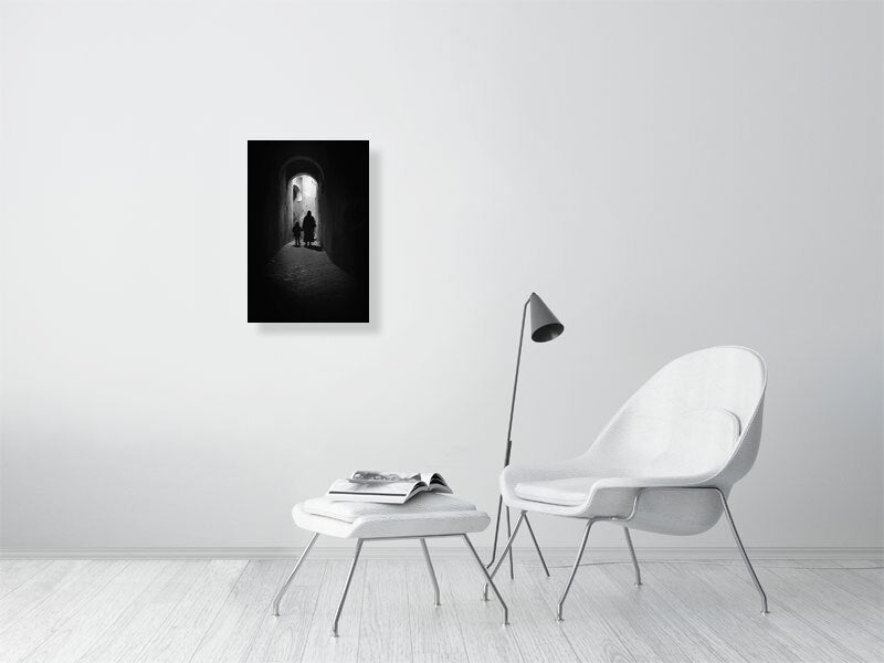 Monochrome photograph of a woman and child walking through a narrow alley under soft daylight. The scene evokes quiet observation and documentary calm — a defining image for the visual tone of Dustlight Archive.