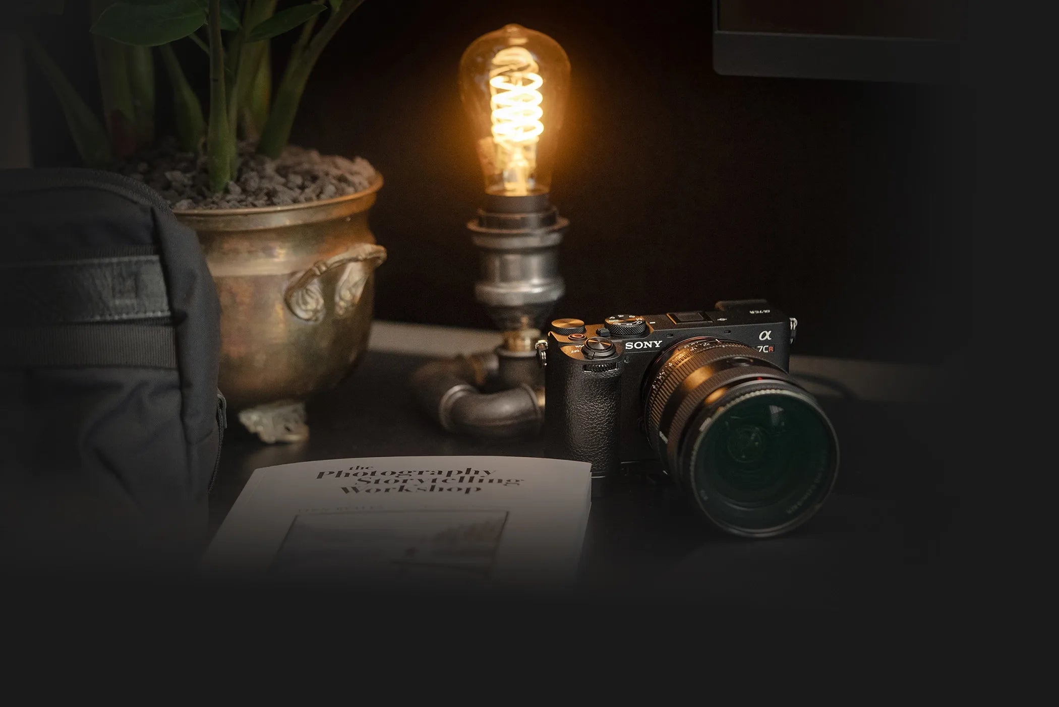 Photographer’s desk with a Sony A7CR, vintage lamp, and storytelling book — offering a quiet glimpse into the creative workspace behind Dustlight Archive.