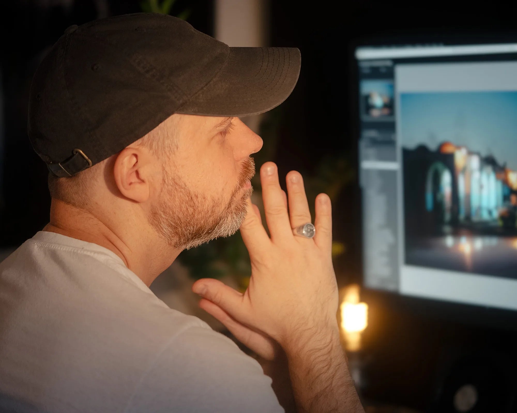 Photographer sitting at his desk in warm light, thoughtfully reviewing an image on screen. The scene captures a quiet, reflective moment between editing and creation — a natural transition into the story behind Dustlight Archive.